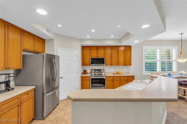 kitchen with pendant lighting, stainless steel appliances, a center island with sink, and sink