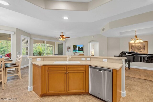 kitchen with ceiling fan with notable chandelier, sink, hanging light fixtures, stainless steel dishwasher, and an island with sink