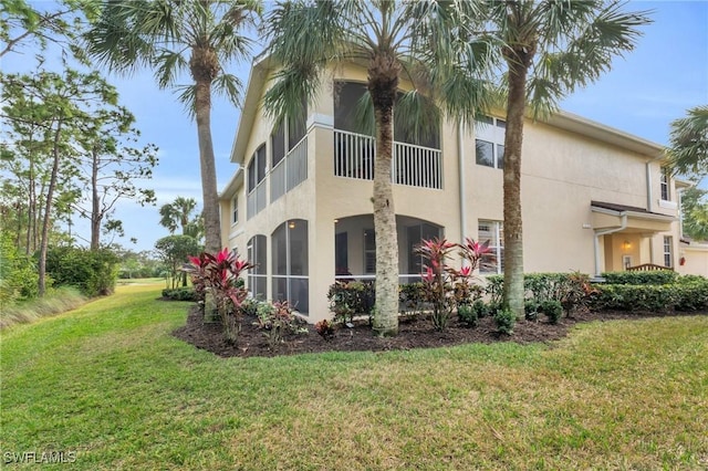 view of side of property with a sunroom and a yard