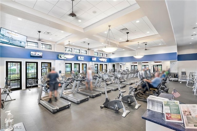 workout area with a towering ceiling, a paneled ceiling, and ceiling fan