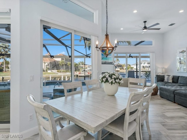 dining space featuring ceiling fan with notable chandelier