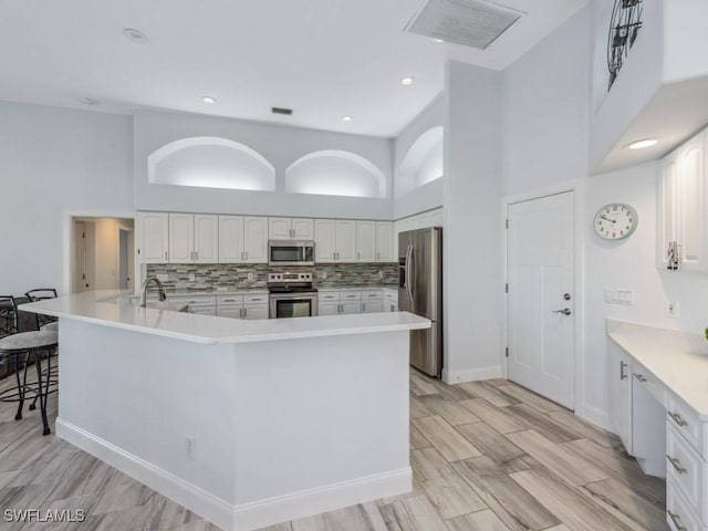 kitchen featuring white cabinets, appliances with stainless steel finishes, and a high ceiling