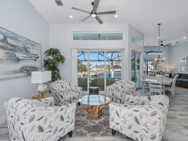 living room featuring a water view and ceiling fan with notable chandelier