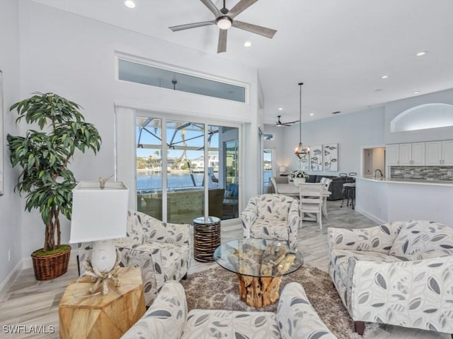 living room with ceiling fan, a water view, and light hardwood / wood-style flooring