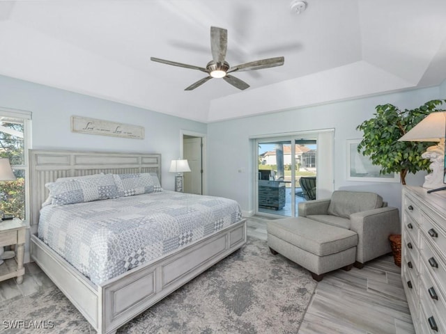 bedroom with ceiling fan, a raised ceiling, access to outside, and light hardwood / wood-style flooring