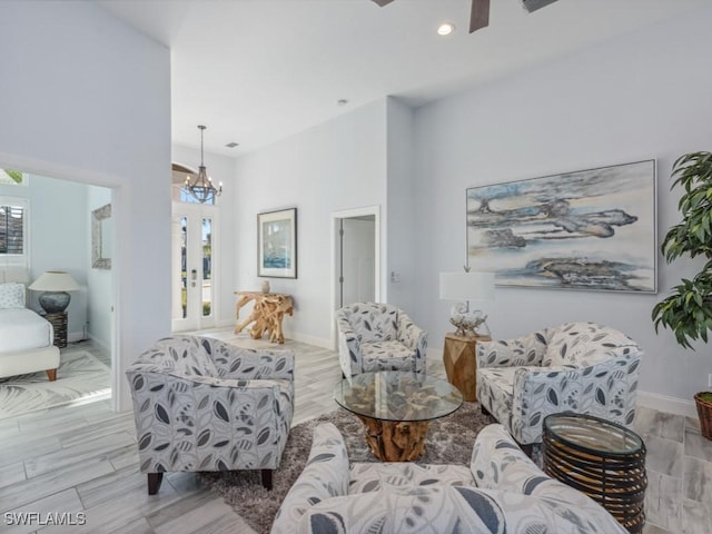 living room with ceiling fan with notable chandelier, plenty of natural light, and a towering ceiling