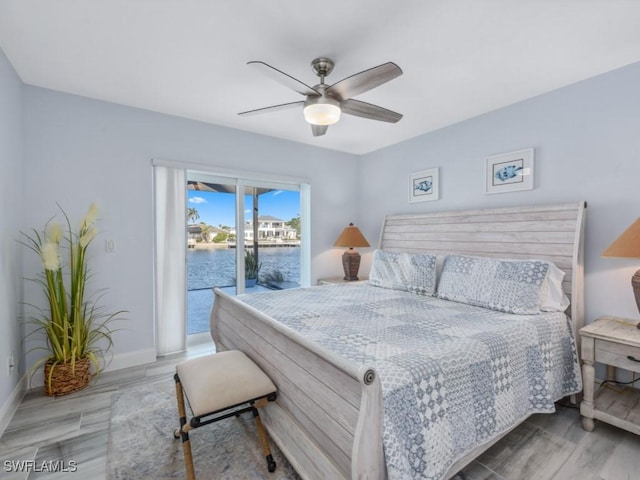 bedroom featuring hardwood / wood-style flooring, ceiling fan, a water view, and access to outside