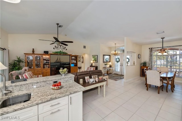 kitchen with light stone counters, sink, white cabinetry, decorative light fixtures, and ceiling fan with notable chandelier