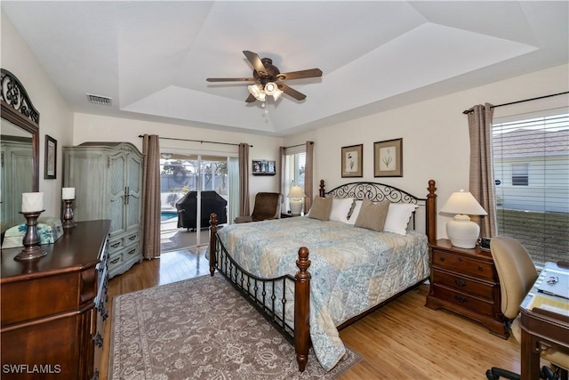 bedroom featuring access to outside, hardwood / wood-style flooring, a raised ceiling, and ceiling fan