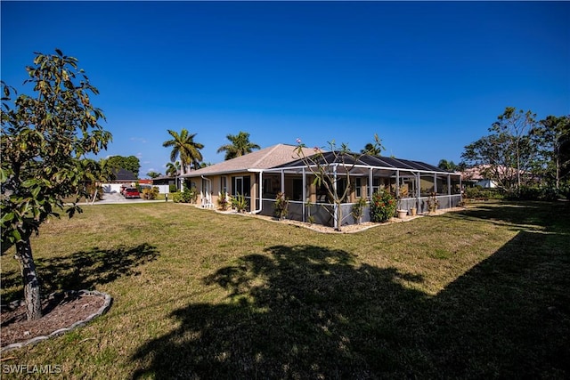 rear view of house with a lanai and a lawn