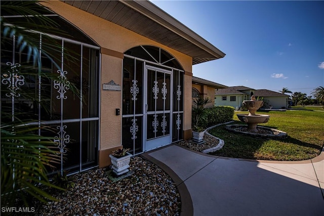 view of exterior entry with a yard