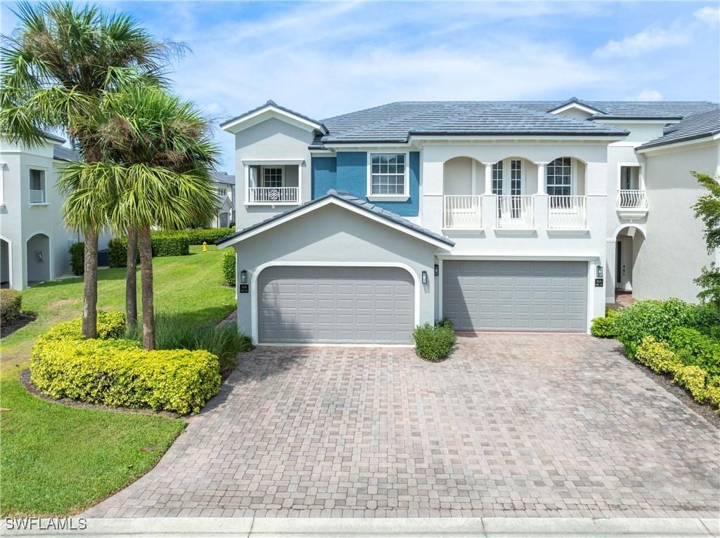 view of front facade featuring a garage, a balcony, and a front yard