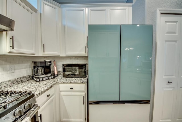 kitchen featuring fridge, white cabinets, and decorative backsplash