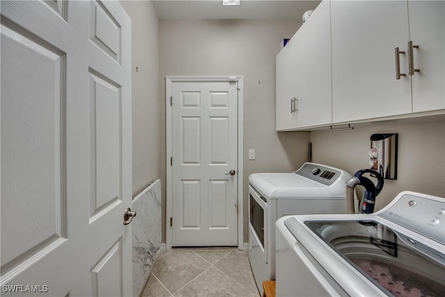 laundry room with cabinet space, separate washer and dryer, and light tile patterned flooring