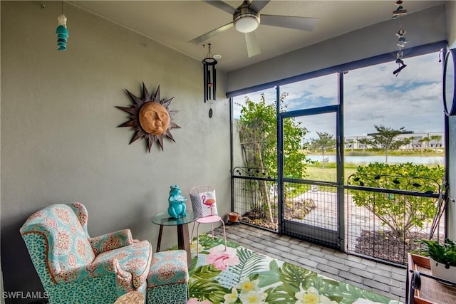 sunroom featuring a water view and a ceiling fan