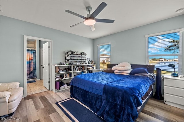 bedroom with ceiling fan, ensuite bath, and light hardwood / wood-style flooring