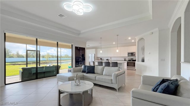 living room featuring a tray ceiling, light tile patterned floors, and a water view