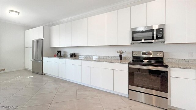 kitchen with white cabinetry, light stone counters, light tile patterned floors, crown molding, and appliances with stainless steel finishes