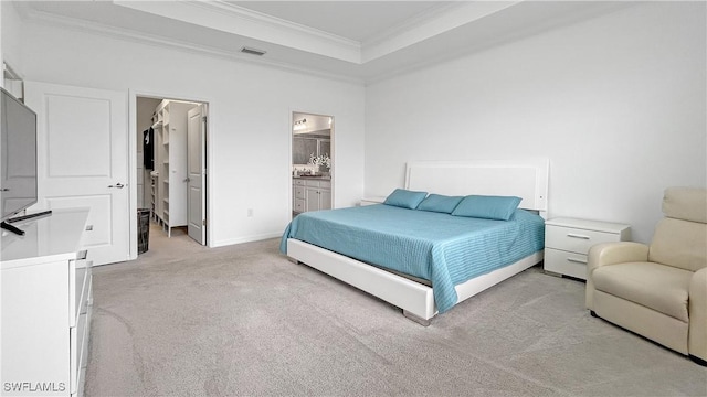 bedroom with crown molding, ensuite bathroom, light carpet, and a tray ceiling