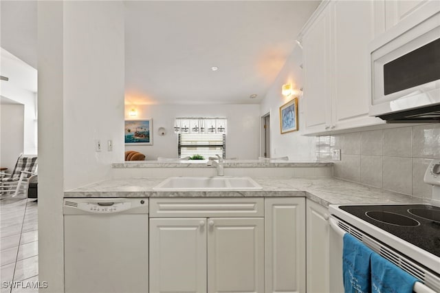 kitchen featuring backsplash, sink, white cabinets, and white appliances