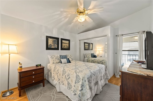 bedroom with ceiling fan, a closet, lofted ceiling, and light wood-type flooring