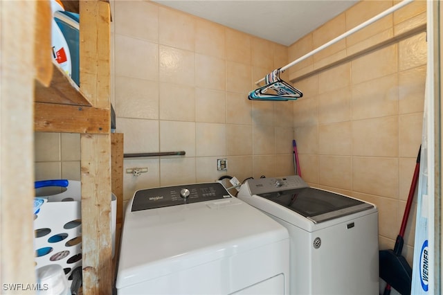 clothes washing area featuring separate washer and dryer and tile walls