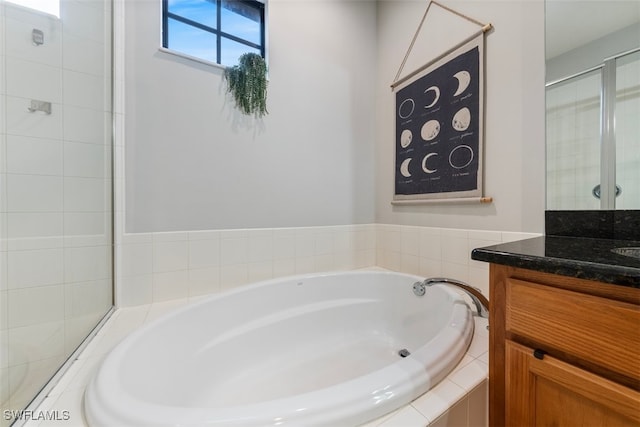 bathroom featuring tiled shower, a bath, and vanity