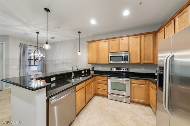 kitchen with a sink, decorative light fixtures, dark stone countertops, stainless steel appliances, and a peninsula