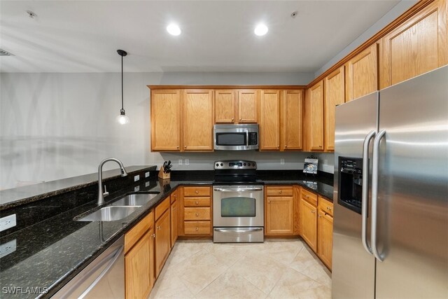 kitchen with sink, dark stone countertops, decorative light fixtures, light tile patterned floors, and appliances with stainless steel finishes