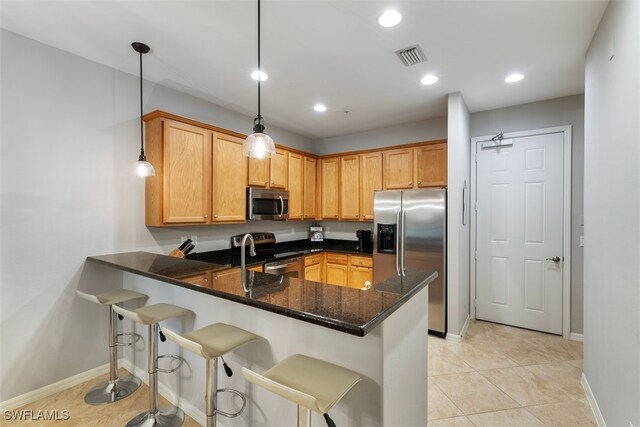 kitchen featuring kitchen peninsula, dark stone counters, stainless steel appliances, sink, and hanging light fixtures