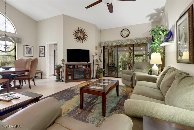 living room featuring vaulted ceiling, a fireplace, and ceiling fan with notable chandelier