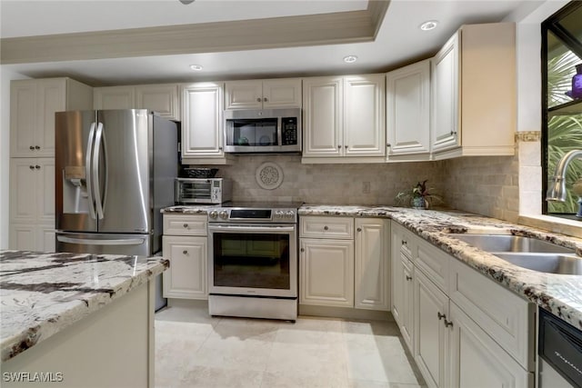 kitchen featuring backsplash, sink, a tray ceiling, stainless steel appliances, and light stone counters