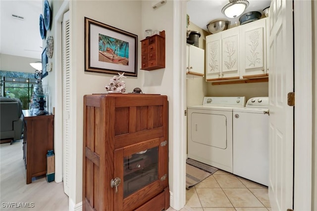 laundry area featuring washer and dryer, cabinets, and light tile patterned floors