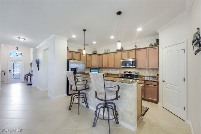 kitchen featuring dark stone counters, appliances with stainless steel finishes, decorative light fixtures, a kitchen island, and a kitchen bar