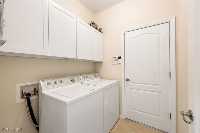 washroom featuring separate washer and dryer, light tile patterned flooring, and cabinets