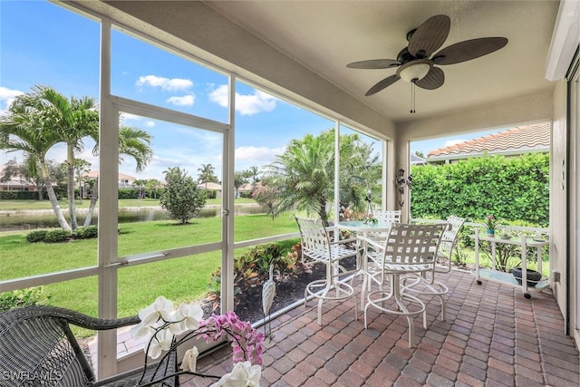 unfurnished sunroom with ceiling fan and a water view