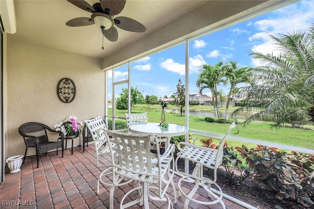 sunroom featuring a water view and ceiling fan