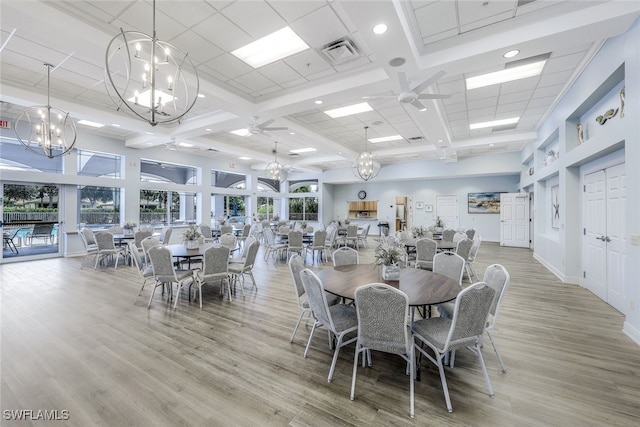 dining area with wood-type flooring, a towering ceiling, ceiling fan, and coffered ceiling