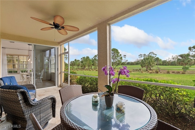 sunroom with ceiling fan and a rural view