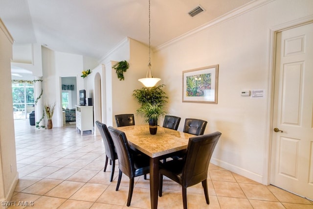 tiled dining area featuring lofted ceiling and crown molding