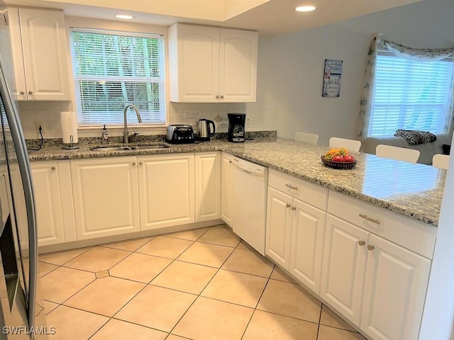 kitchen featuring light stone counters, dishwasher, white cabinets, and sink