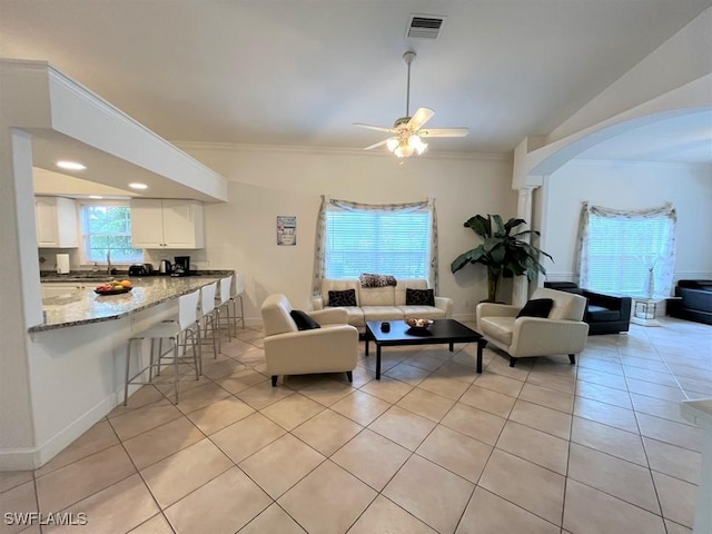 living room featuring ceiling fan, light tile patterned floors, and crown molding