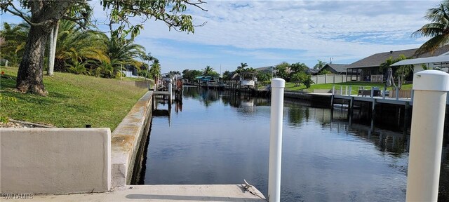 view of dock with a lawn and a water view