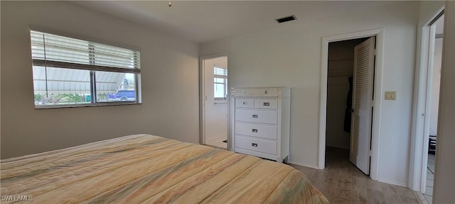 bedroom with light wood-type flooring, a walk in closet, and a closet