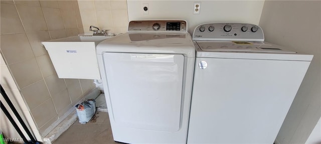 washroom featuring sink, tile walls, and washing machine and clothes dryer