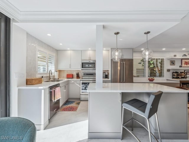 kitchen featuring a kitchen island, pendant lighting, sink, white cabinets, and stainless steel appliances