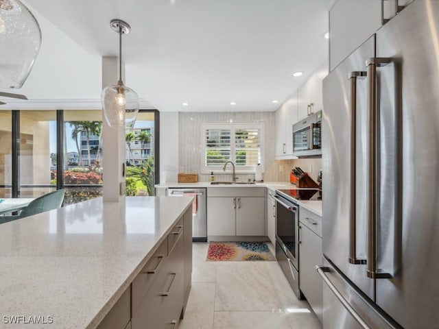 kitchen with sink, hanging light fixtures, stainless steel appliances, tasteful backsplash, and light stone countertops