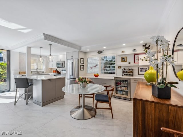 kitchen featuring wine cooler, decorative light fixtures, appliances with stainless steel finishes, a kitchen island, and white cabinets