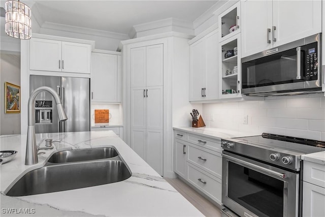 kitchen featuring tasteful backsplash, white cabinets, stainless steel appliances, and ornamental molding