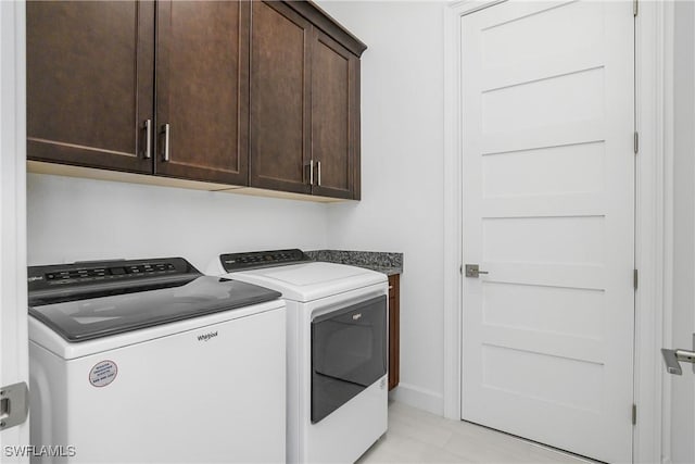 clothes washing area with baseboards, cabinet space, and washing machine and dryer